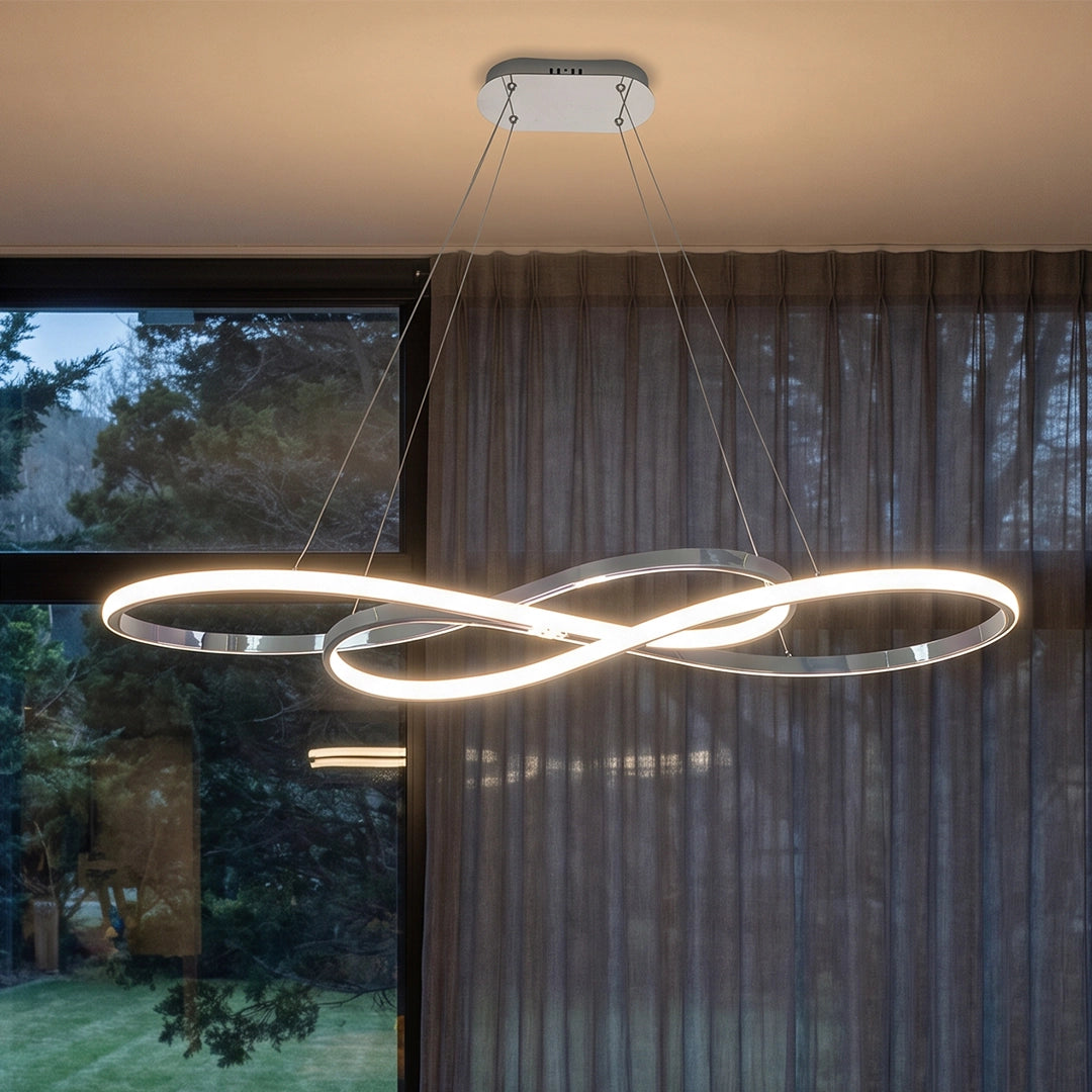 LED infinity chandelier close-up showing the intertwined loop shape, slim suspension cables, and warm glowing light.