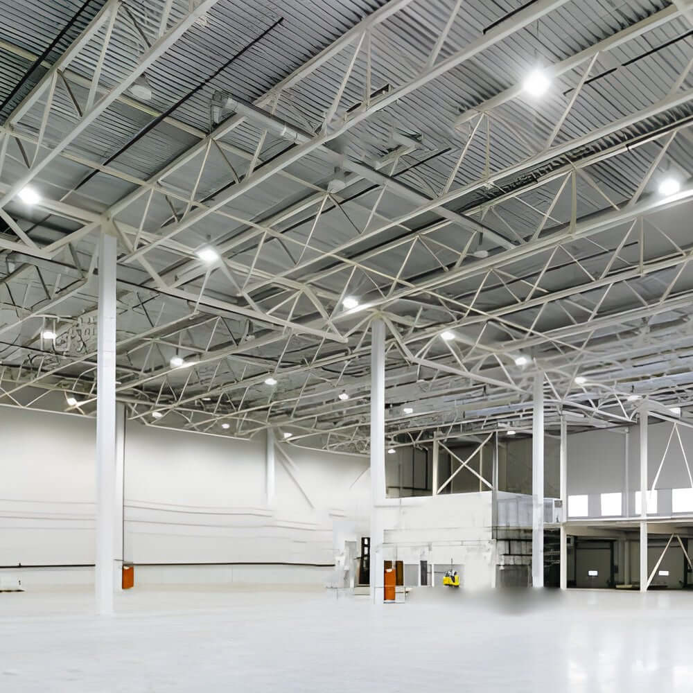 LED lamp for warehouse illuminating a large storage area with high ceilings and metal racks.