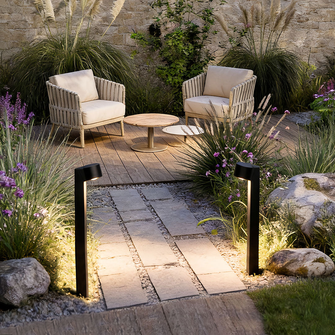 LED landscape path lighting lining a stone garden path that leads to an outdoor seating area.