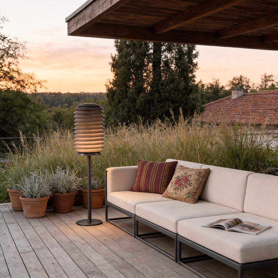LED light bollard with a sleek design, illuminating an outdoor seating area at dusk.
