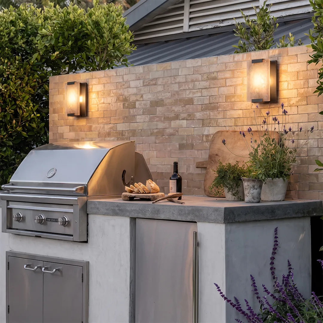 LED light wall lamp fixtures illuminating an outdoor kitchen and stone patio wall.