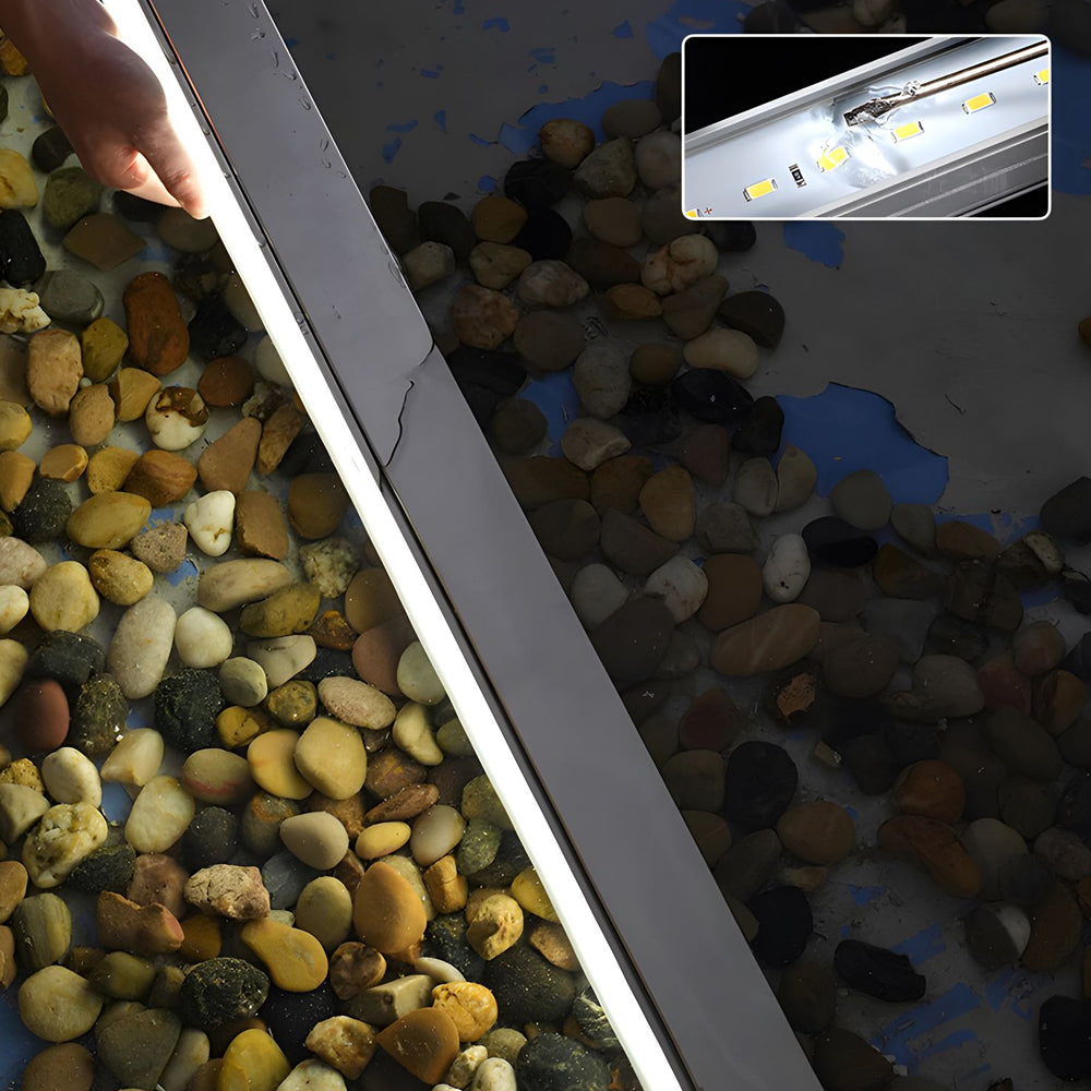 LED strip lighting installed in aluminum channel among decorative river stones creating subtle landscape accent lighting