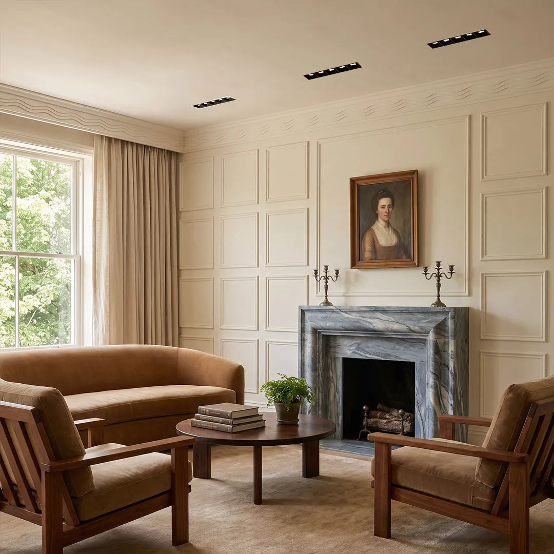 LED linear downlight fixtures installed across a bright living room ceiling above a fireplace and seating area.