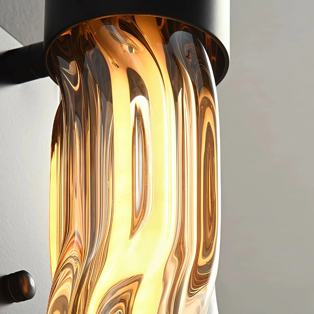 Close-up of an LED linear wall light featuring a sculpted amber glass diffuser and warm illumination.