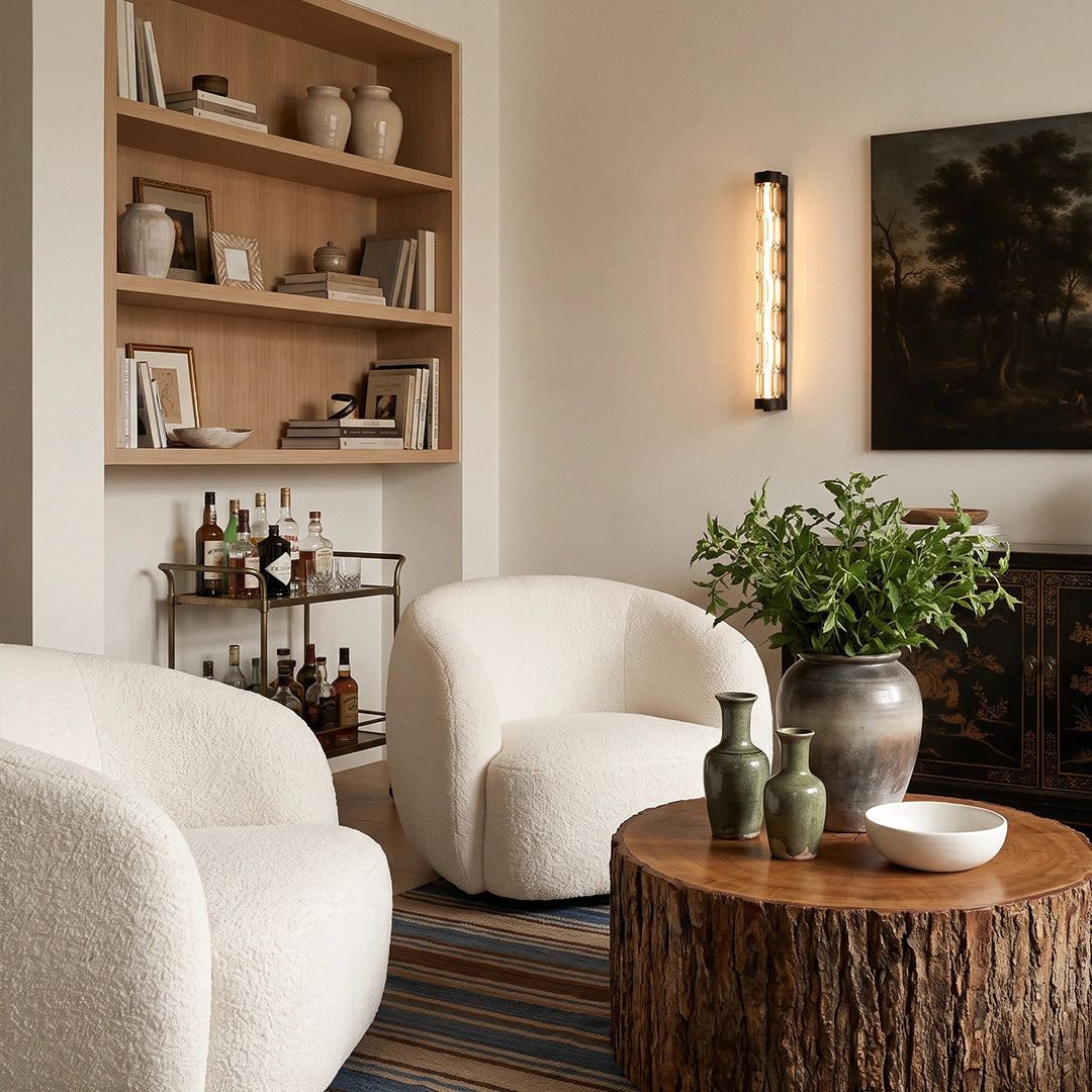LED linear wall light mounted above boucle chairs in a modern living room with built-in shelving.