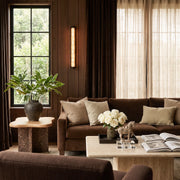 LED linear wall light illuminating a warm living room with a dark wood feature wall and neutral sofa.
