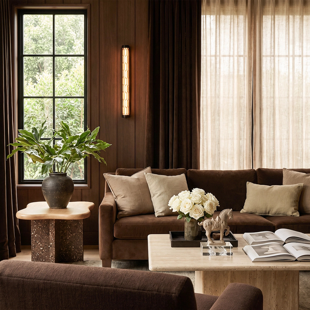 LED linear wall light illuminating a warm living room with a dark wood feature wall and neutral sofa.