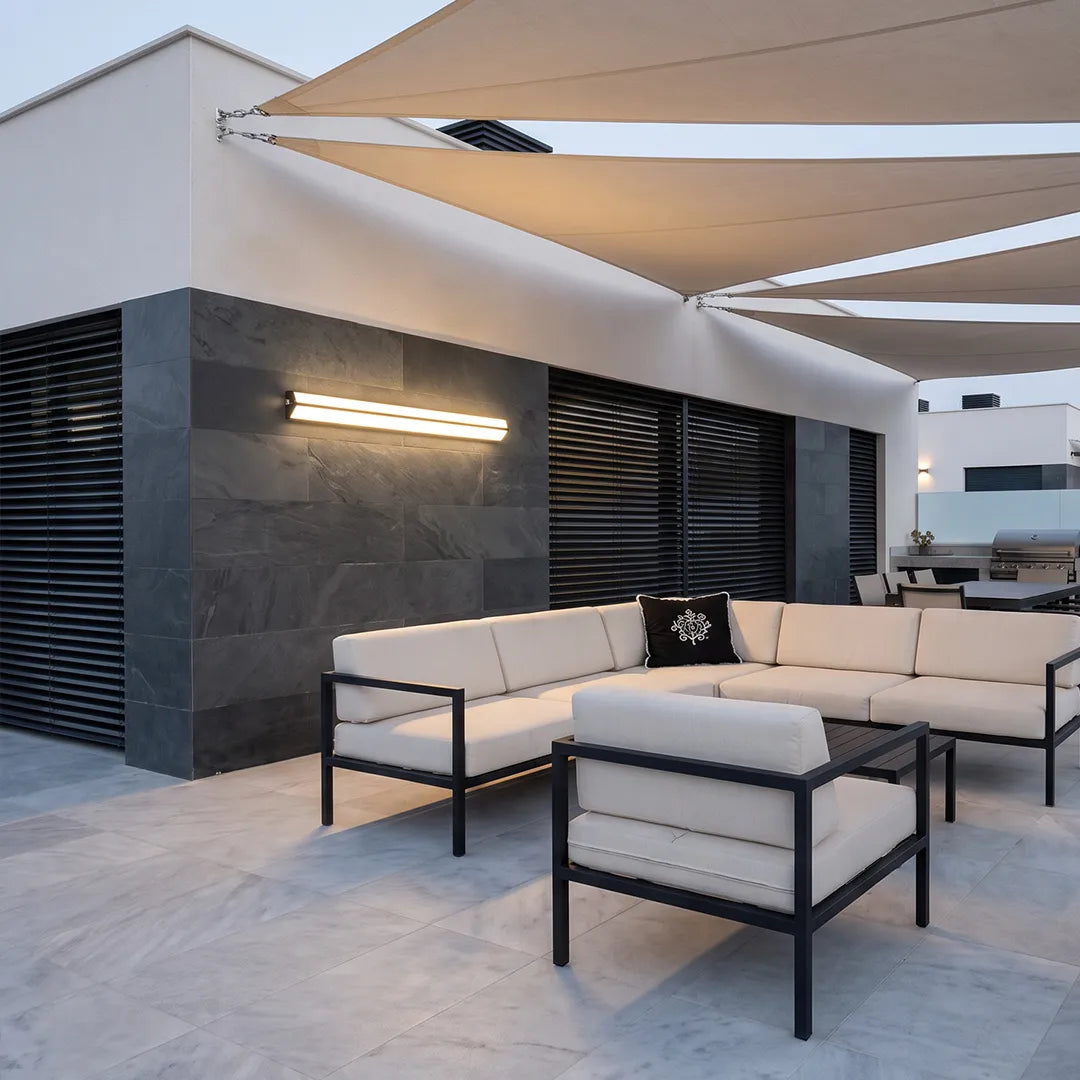 LED linear wall sconce mounted on a contemporary patio wall beside outdoor seating and shade sails.