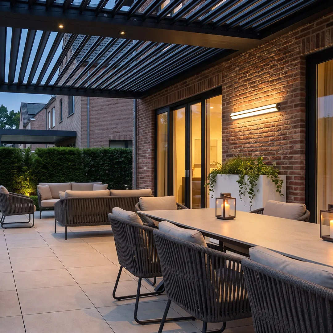 LED linear wall sconces lighting a covered brick patio with a long outdoor dining table.