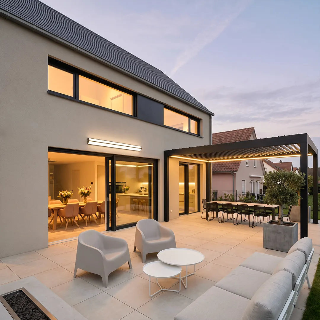 LED linear wall sconce illuminating a modern backyard patio with outdoor lounge seating.