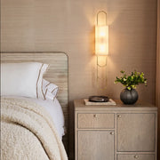 LED modern wall sconce mounted beside a bedside cabinet with a frosted shade and warm ambient glow.