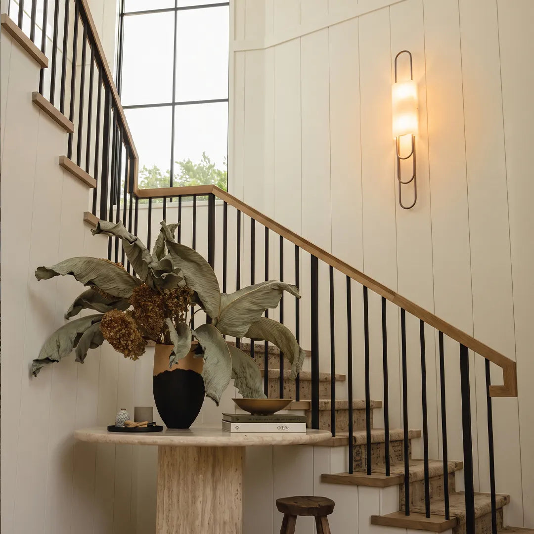 LED modern wall sconce installed along a staircase wall with a slim vertical design and warm lighting.