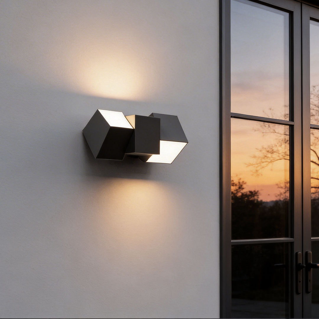 LED outdoor lighting wall mount with a modern geometric design, illuminating a white exterior wall.