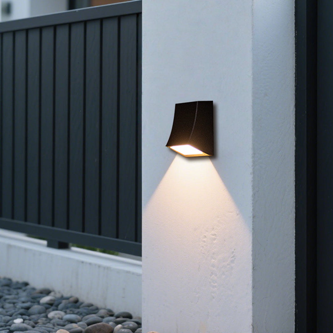 LED outdoor wall sconce installed beside a fence, enhancing outdoor ambiance with modern lighting.