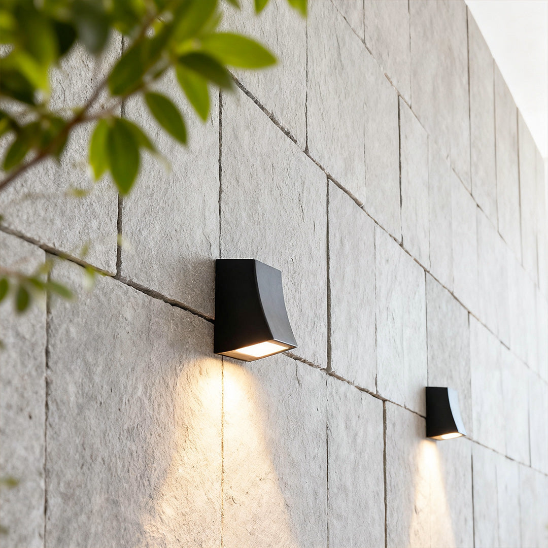 LED outdoor wall sconce with a sleek design, casting a soft glow on a textured wall.