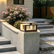 LED pillar lights mounted on a concrete post beside outdoor steps, casting a warm glow over a modern garden entrance.