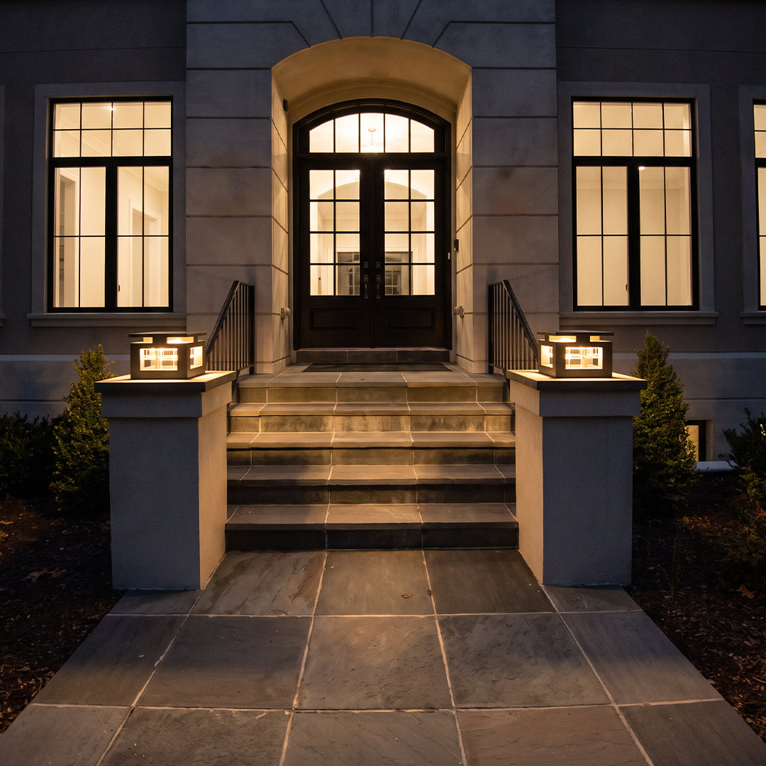 LED pillar lights placed on entry gate columns, illuminating the front steps of a contemporary home at night.