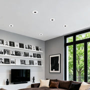 LED recessed spotlights providing task lighting in modern living room with built-in shelving and large windows