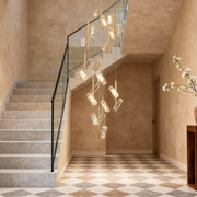 Led staircase chandelier providing ambient illumination in Mediterranean-style stairwell with textured plaster walls