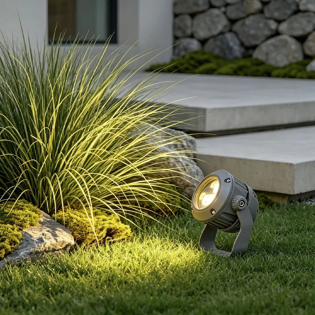 LED tree spotlight shining on ornamental grass beside outdoor stone steps.