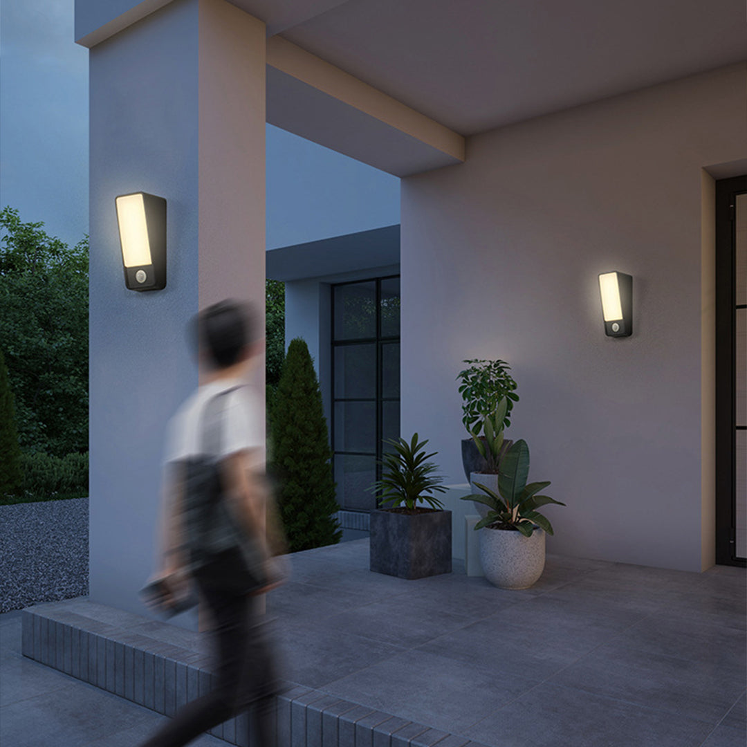 Multiple LED wall fixtures creating ambient lighting on modern patio with person walking