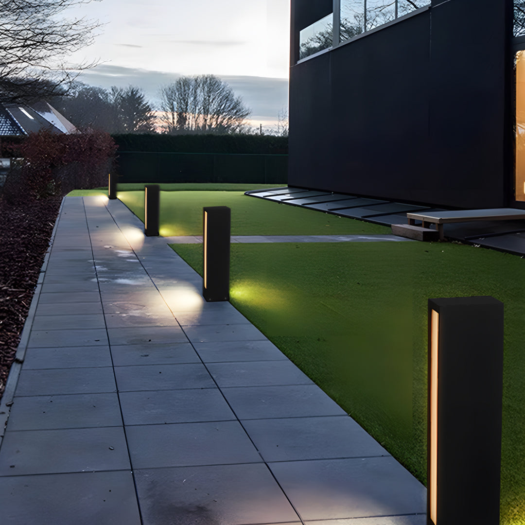 Long exterior walkway lit by warm modern led wall light outdoor posts arranged along the path.