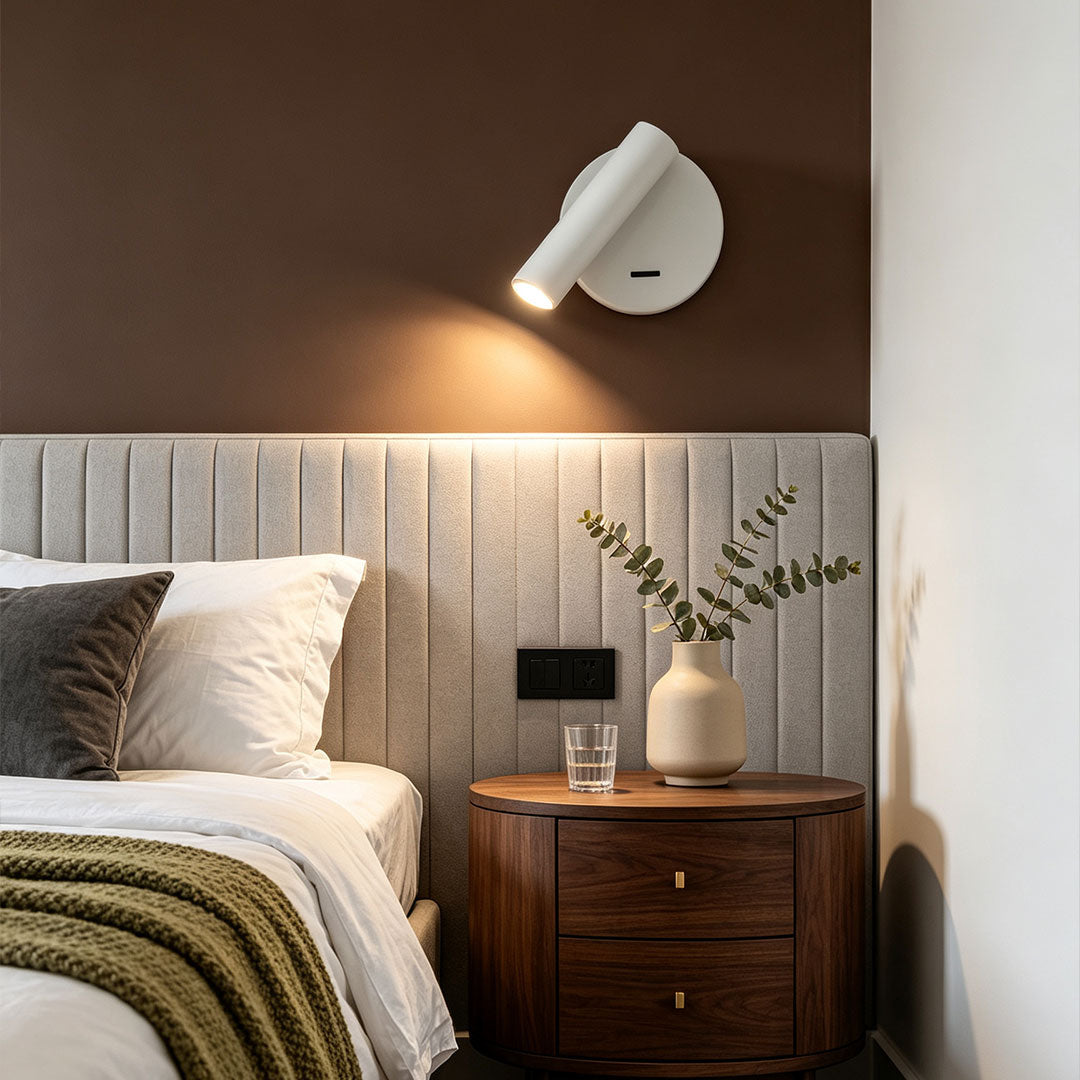 Contemporary LED wall reading light above bedside table with adjustable white spotlight fixture.