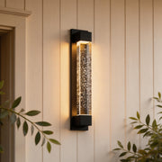 LED wall sconce outdoor mounted on beige siding, modern vertical bubble glass light for exterior decor.