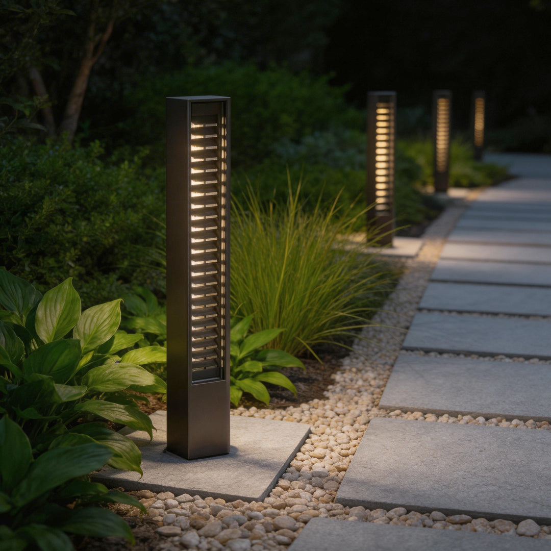 LED wall sconce outdoor bollard lighting along garden pathway, multiple fixtures creating soft illuminated walkway.