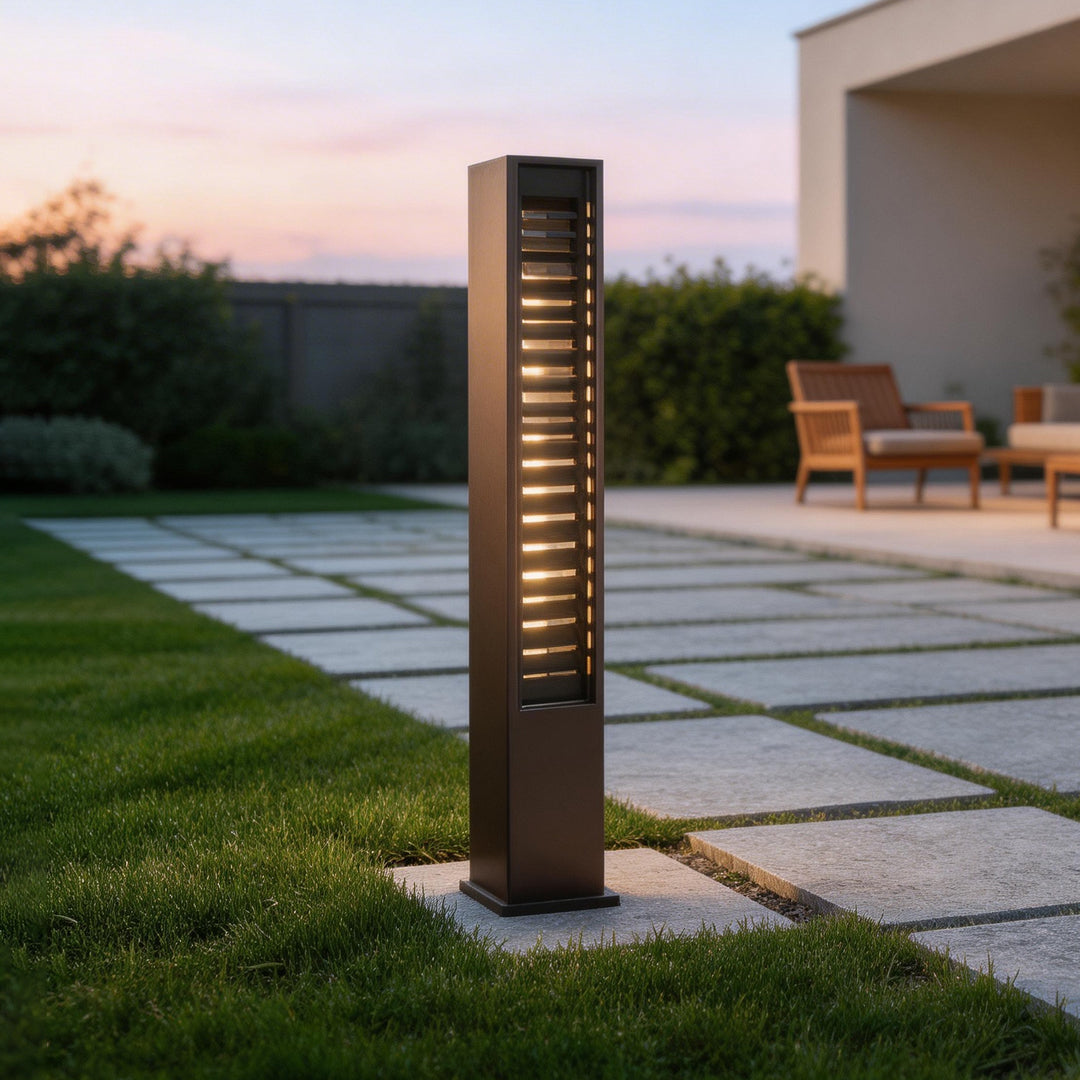 LED wall sconce outdoor bollard light on lawn path, minimalist vertical fixture with warm ambient lighting.