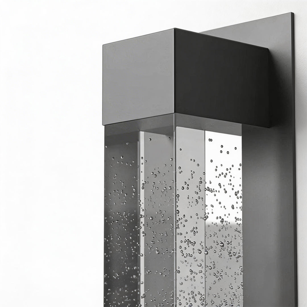 LED wall sconce outdoor product close-up showing black metal top and clear bubble glass cylinder detail.