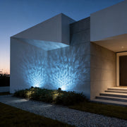 LED wall sconce outdoor exterior spotlights casting blue light patterns on modern building facade at night.