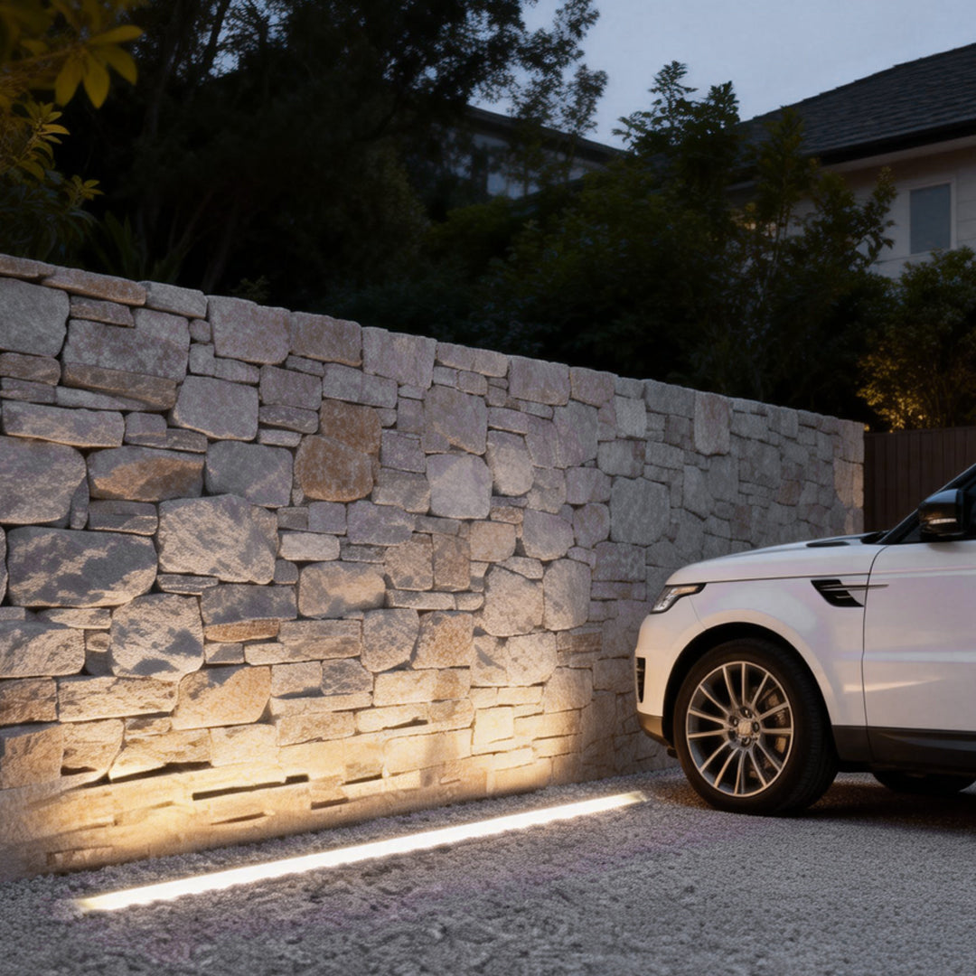 LED wall washer light installed along a stone wall, providing subtle and elegant outdoor pathway lighting.