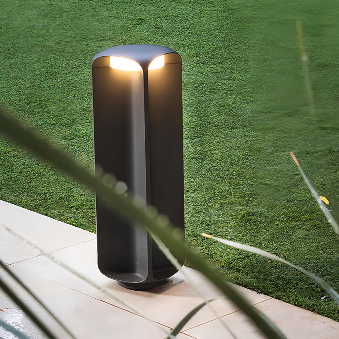 Tall double-head light bollard positioned on green lawn, creating ambient outdoor lighting.
