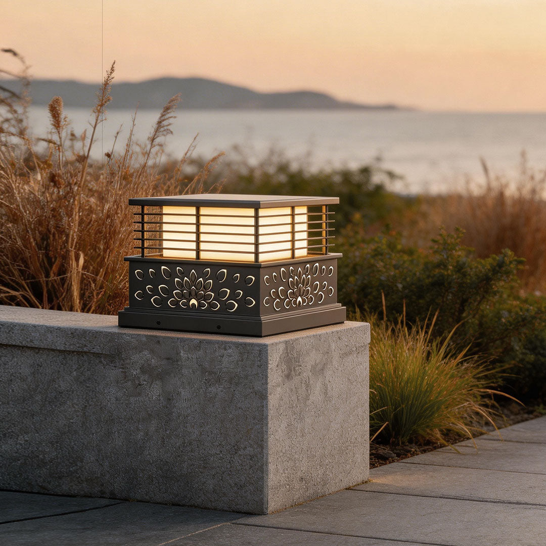 Decorative light pillar for home with intricate cut-out patterns, illuminating a pathway at dusk.