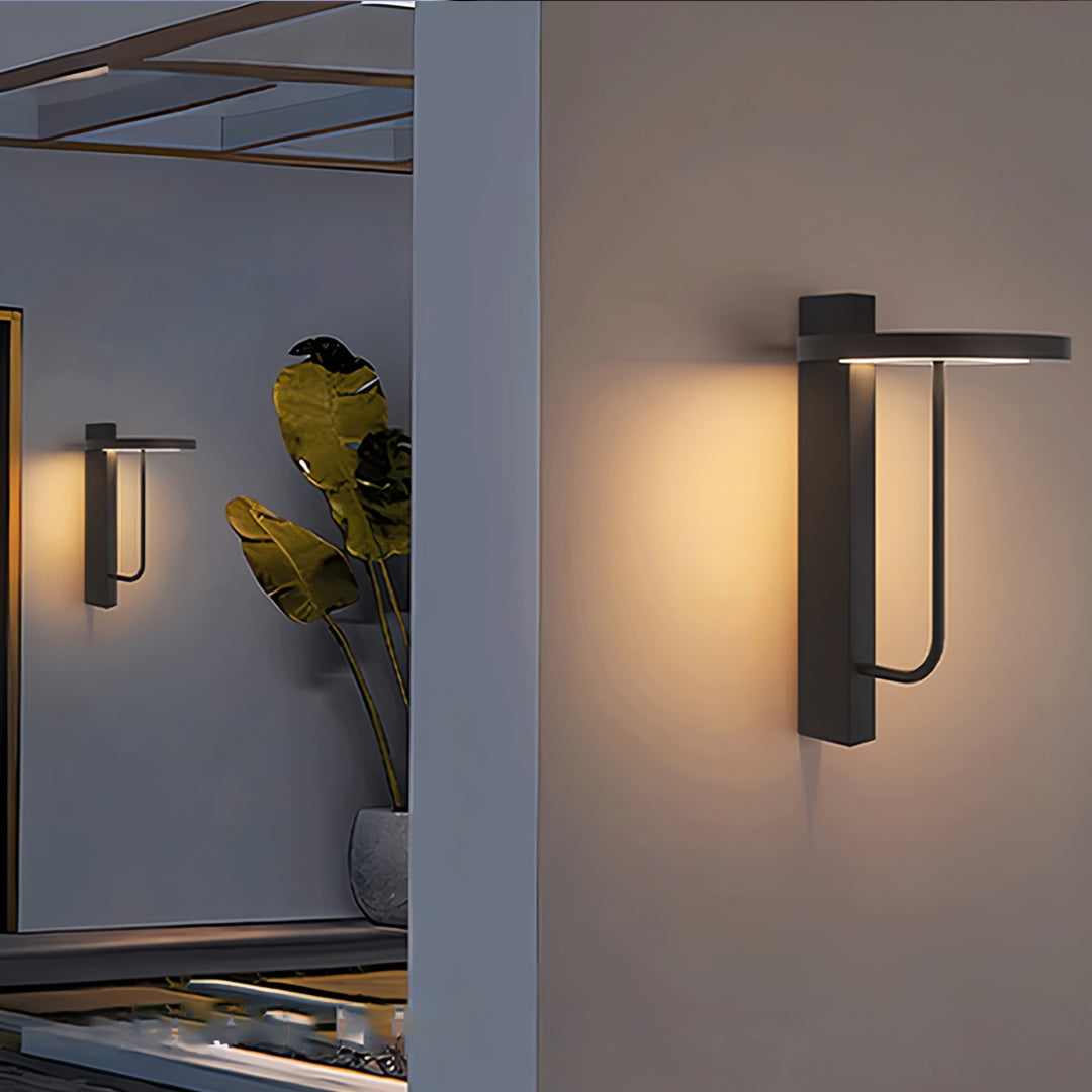 Single modern light sconces outdoor fixture glowing softly on a minimalist exterior wall at dusk.