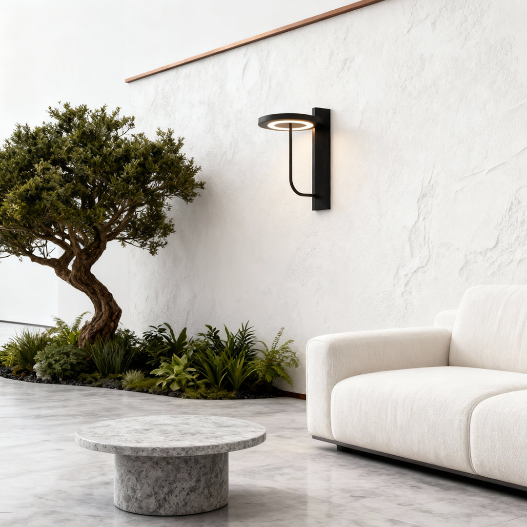 Light sconces outdoor installed along a clean white wall beside a garden seating area.
