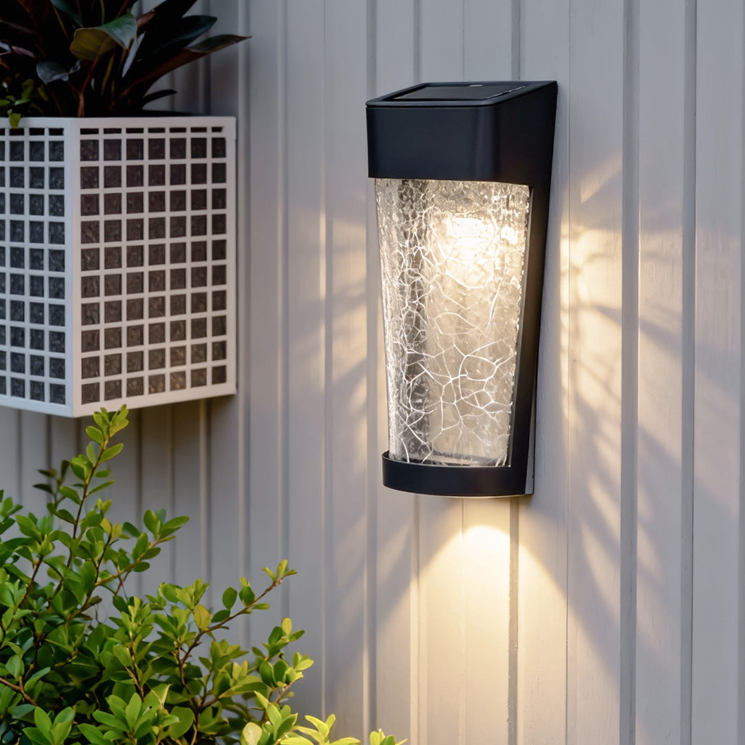 A contemporary outdoor wall lantern with ribbed glass mounted on a light exterior wall, enhancing the space with modern lighted outdoor wall decor.