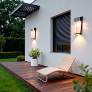 A glowing outdoor wall lantern installed beside a cozy patio area, adding inviting and atmospheric lighted outdoor wall decor.