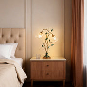 Lily table lamp illuminating a cozy bedside table with warm, floral-inspired glow.
