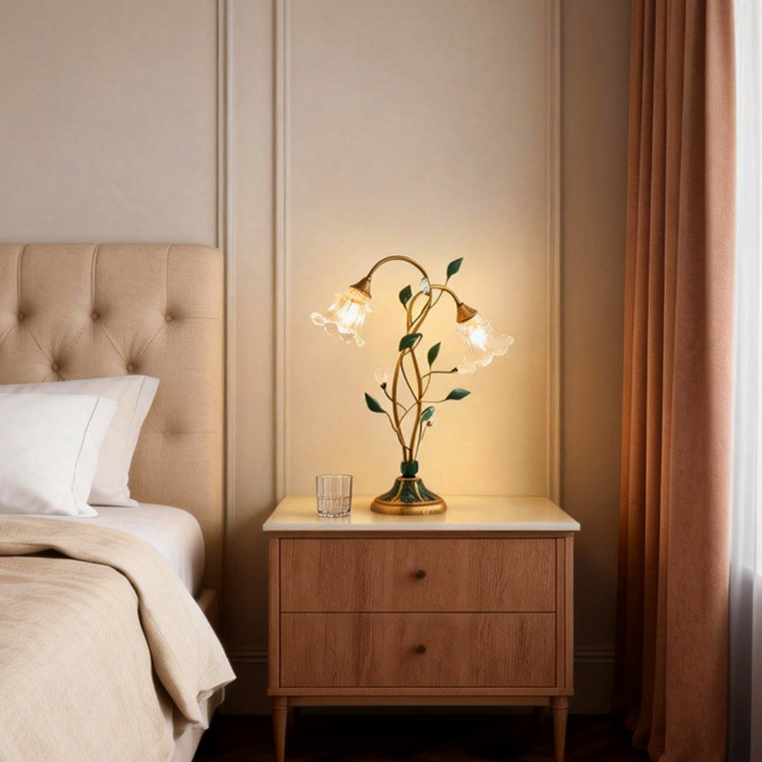 Lily table lamp illuminating a cozy bedside table with warm, floral-inspired glow.