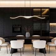 A sleek line wave pendant light hanging over a modern kitchen island, creating a minimalist and contemporary atmosphere with its smooth curves.