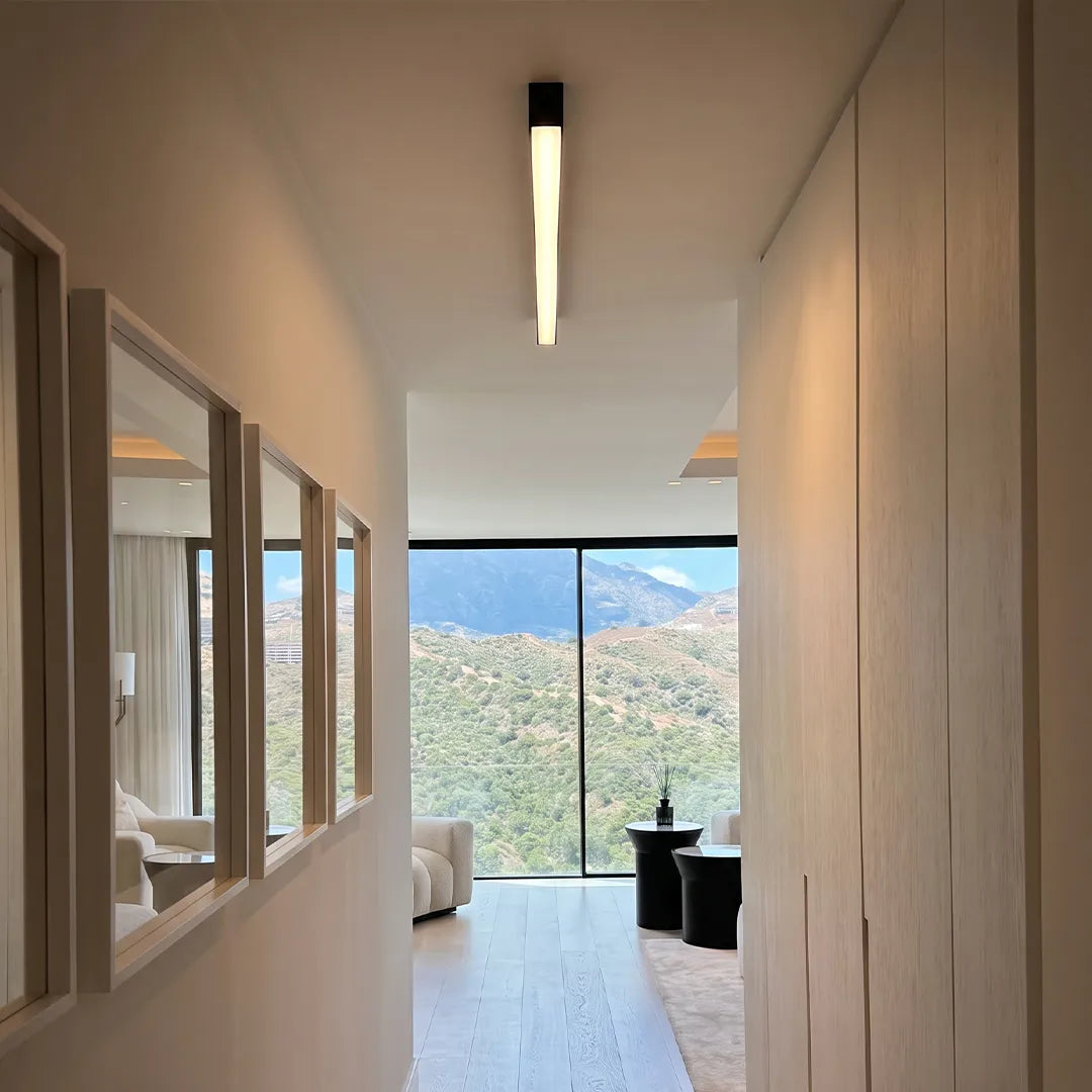 Linear ceiling light installed in a modern hallway with wood walls and a large window view.