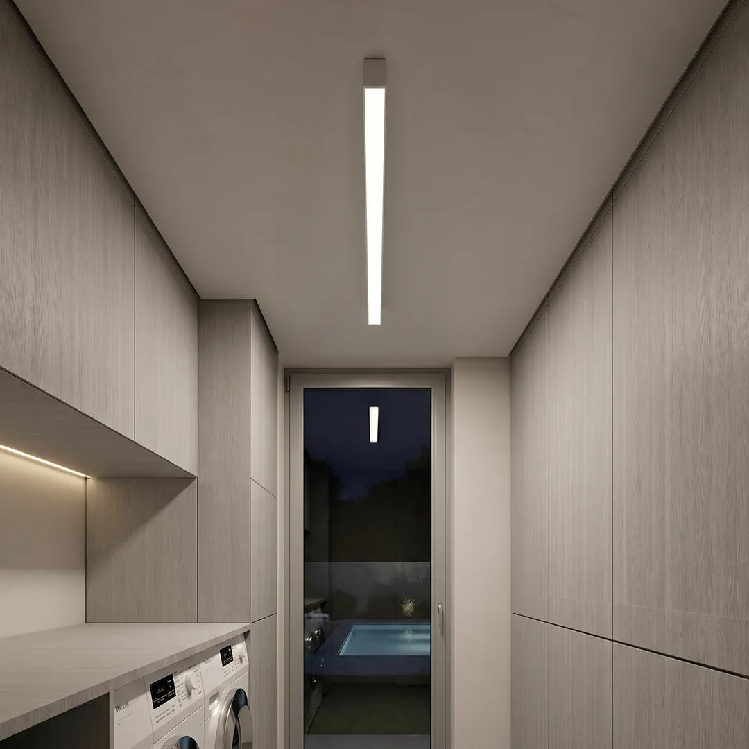 Linear ceiling light installed in a narrow modern interior, delivering bright overhead lighting above a sleek built-in cabinet area.