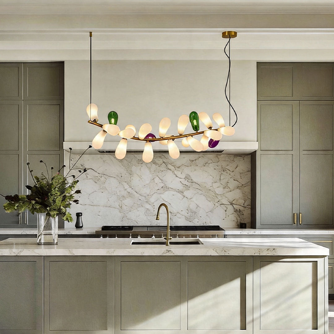 Linear modern chandelier with colorful glass shades installed above a kitchen island in a contemporary space.
