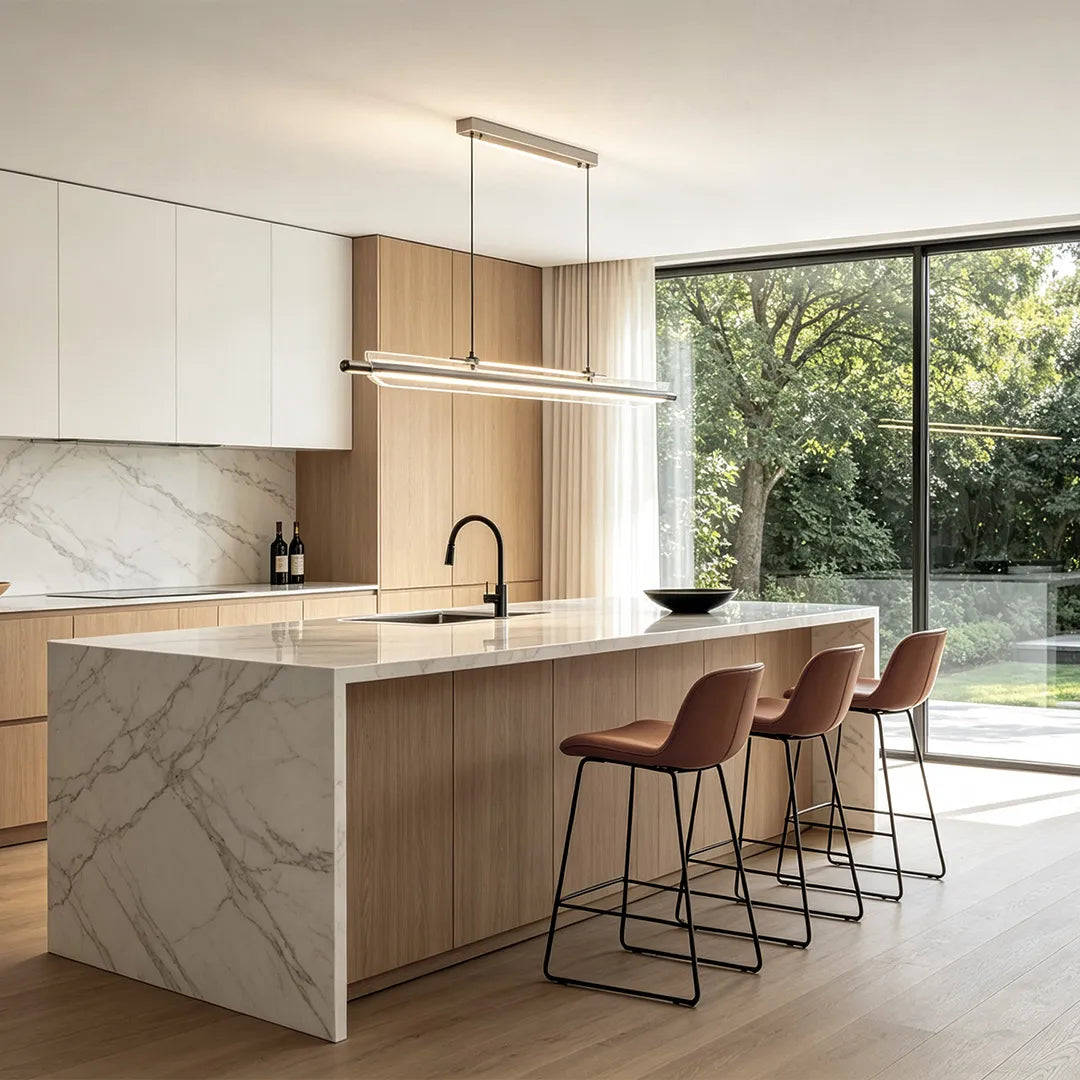 Linear LED pendant light illuminating a contemporary kitchen island with marble and wood cabinetry.