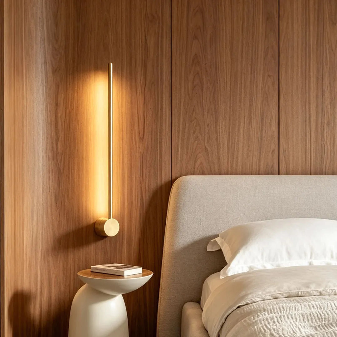 Linear LED wall light positioned above a bedside table against a warm wood accent wall in a cozy bedroom.