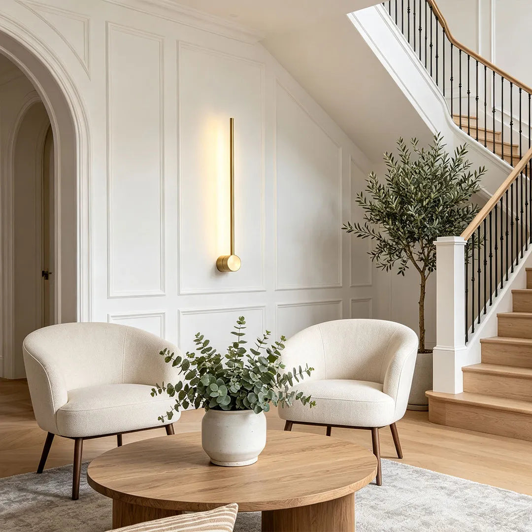 Linear LED wall light mounted beside a staircase in a bright modern living space with soft neutral seating.