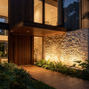 Linear LED wall washer illuminating a modern stone entry wall with warm architectural uplighting.