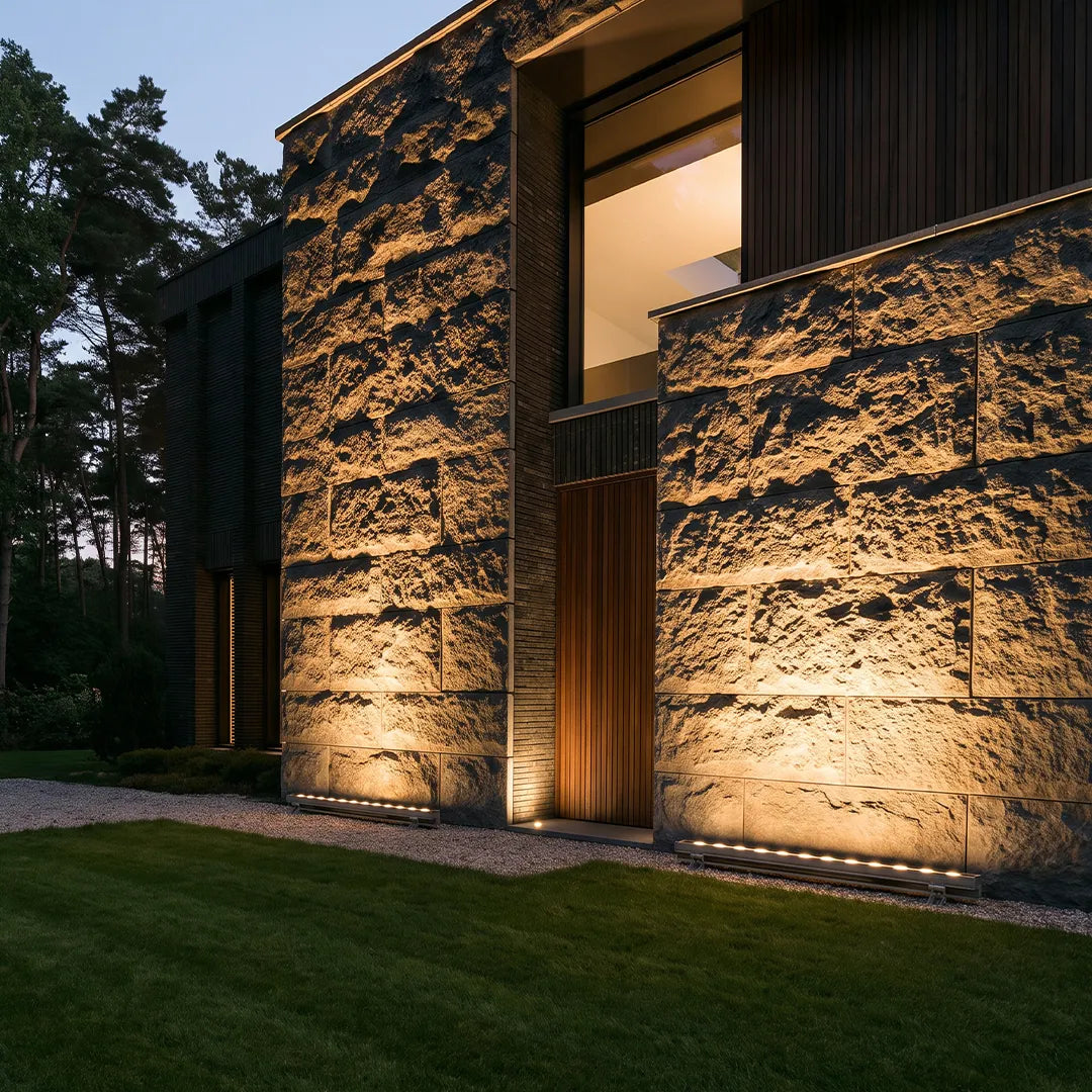 Linear LED wall washer installed along a textured exterior wall to create dramatic vertical light effects at night.
